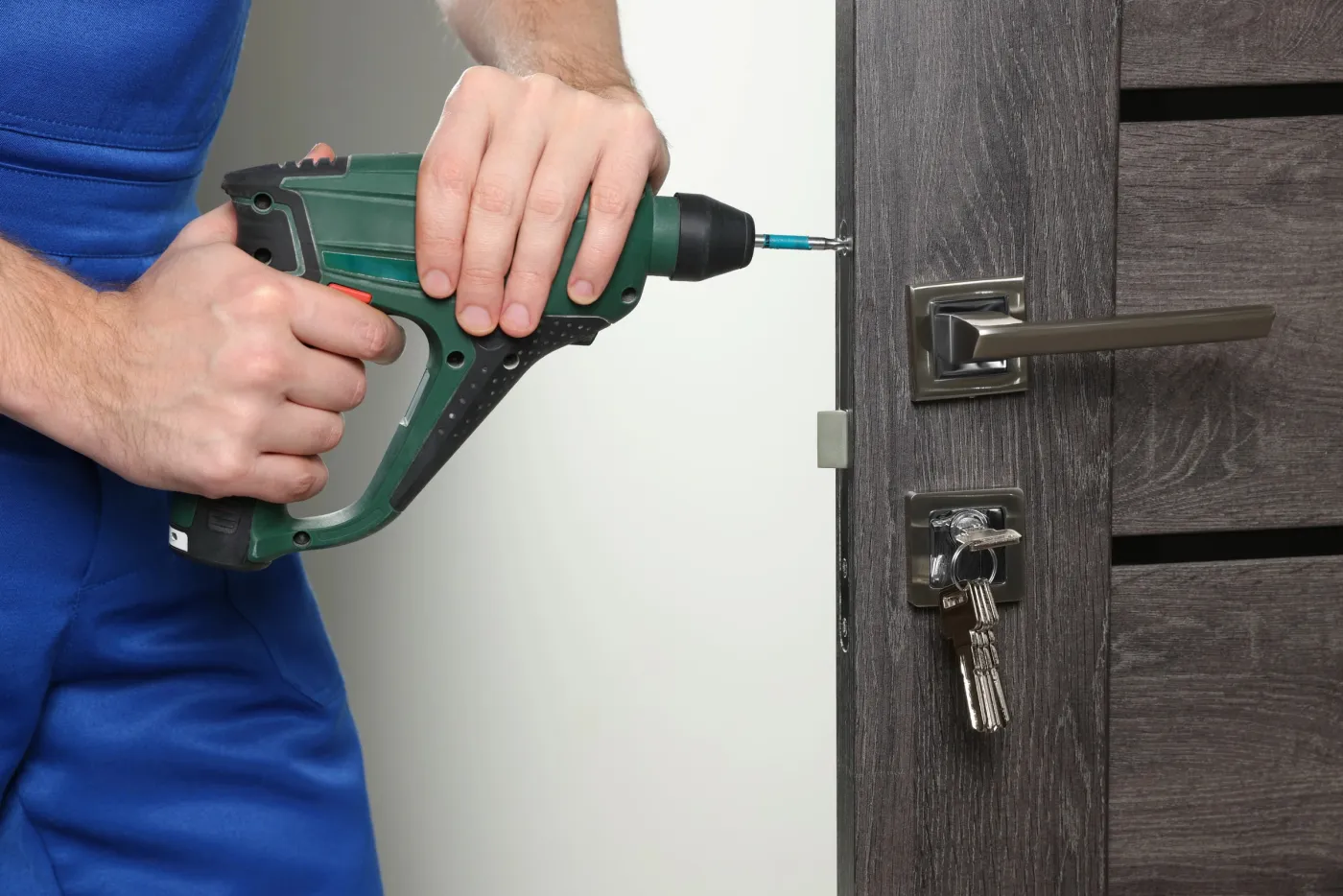 Artisan ajustant une serrure de sûreté sur une porte d'appartement d'un immeuble du 15e à Paris